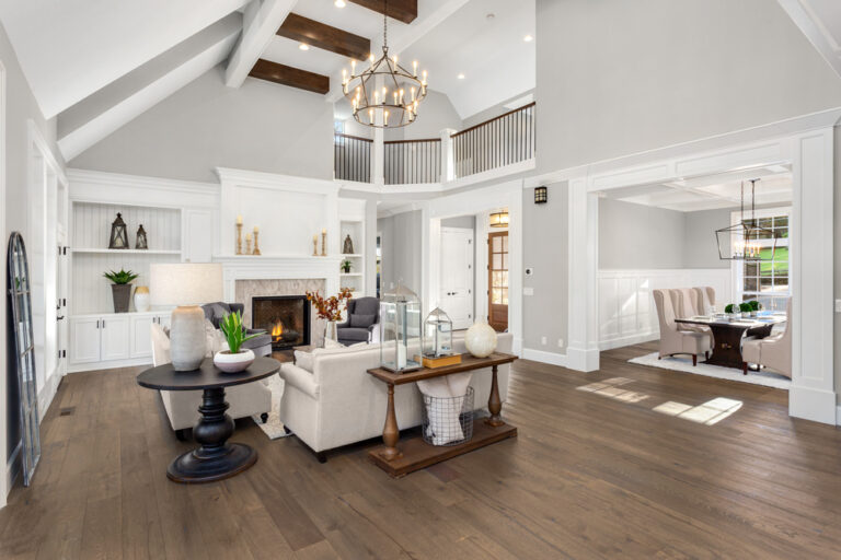 Beautiful living room in new traditional style luxury home. Features vaulted ceilings, fireplace with roaring fire, and elegant furnishings.