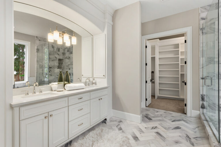 Master bathroom in new luxury home with double vanity and view of walk-in closet